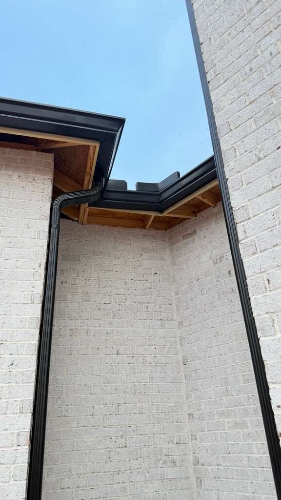 Beautiful black seamless gutters installed on white brick